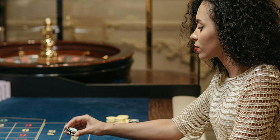 woman betting and placing casino chips on a roulette table