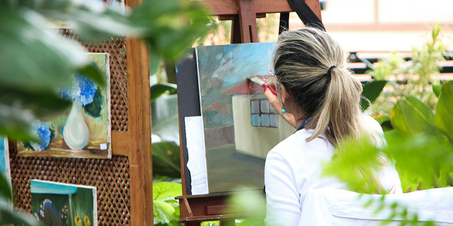 a woman painting an artwork outside at a garden