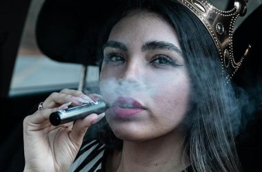 a woman wearing a crown and vaping inside a car